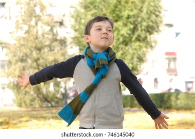 Boy running across the yard from the joyful feeling of freedom. A long scarf is tied around the boy's neck