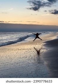 Boy running down the beach at sunset
