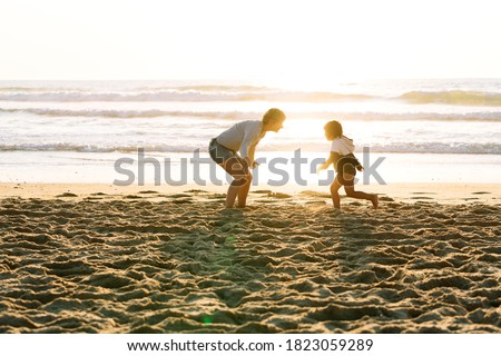 Boy running to his mother to hug her happily on a sunset at the beach