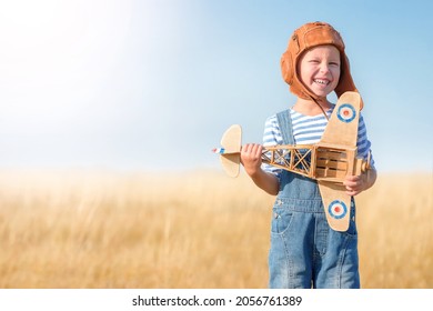 Boy are running on the grass in the open air. Cheerful and happy child play in the field and imagine themselves to be pilot on a sunny summer day. Kid dream of flying and aviation in a retro style. - Shutterstock ID 2056761389