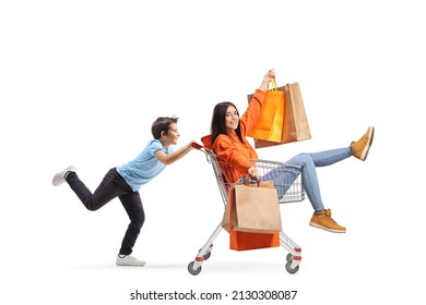 Boy Running And Pushing A Young Female Inside A Shopping Cart With Shopping Bags Isolated On White Background