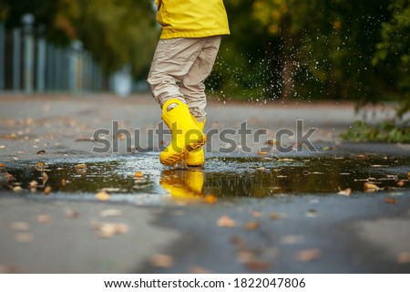 Similar – Image, Stock Photo Small infant boy wearing yellow rubber boots and yellow waterproof raincoat standing in puddle on a overcast rainy day. Child in the rain.