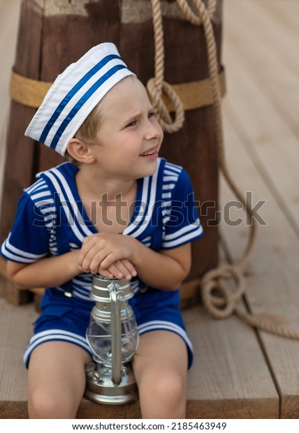 \
A boy in a sailor suit plays against the\
backdrop of a wooden ship in the park. Portrait of a boy in a\
sailor suit.\
marine decor, marine\
paraphernalia.