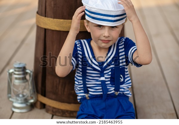 \
A boy in a sailor suit plays against the\
backdrop of a wooden ship in the park. Portrait of a boy in a\
sailor suit.\
marine decor, marine\
paraphernalia.