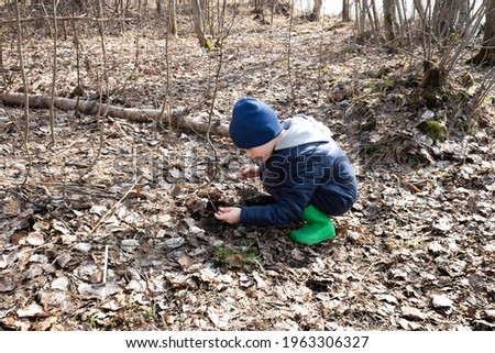 the boy sat down and did something in the ground, holding a worm in his hands, a spring day. concept of outdoor recreation and travel. cpy space.