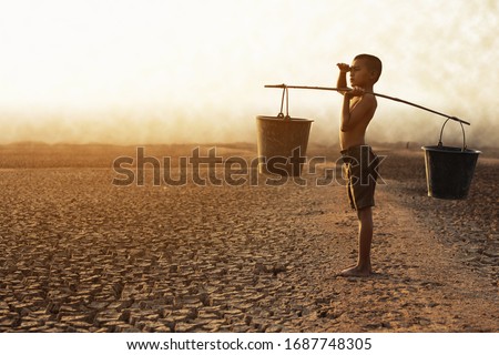 The boy sat on a parched ground due to water shortage due to global warming. Global warming and climate change concept
