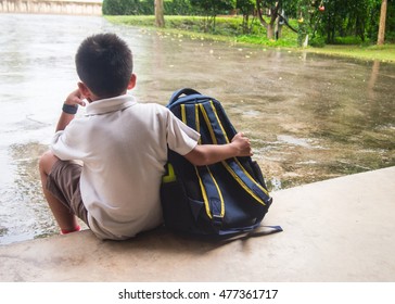 Boy And Schoolbag Waiting For Parent While The Raining