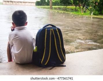 Boy And Schoolbag Waiting For Parent While The Raining