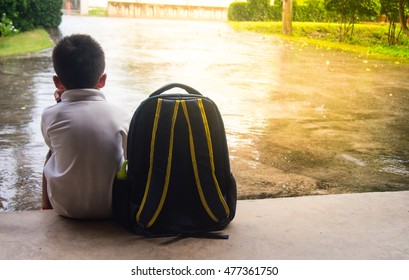 Boy And Schoolbag Waiting For Parent While The Raining