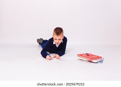 boy schoolboy writes in a notebook on a white background lying down