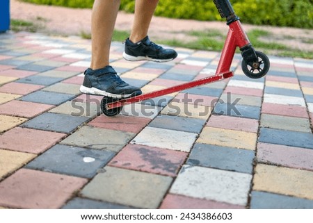 A boy with a scooter in the park, close-up on his feet and the scooter, epitomizing the joy of outdoor activities and childhood play. Stock photo © 