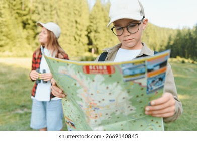 Boy scout reading map while hiking in forest with girl holding binoculars, enjoying outdoor adventure
