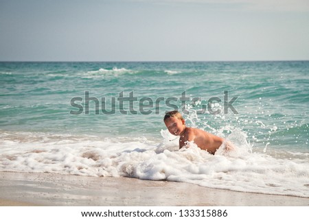 boy at the sea lying in the sand and waves