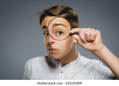 Boy See Through Magnifying Glass, Kid Eye Looking With Magnifier Lens Over Gray