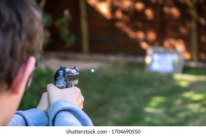 Boy Shoots White Plastic Bb Pellet At Target In Garden With Electric Airsoft Pistol