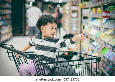 A Boy Is Shopping With His Mom In A Supermarket.