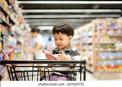 A Boy Is Shopping With His Mom In A Supermarket.