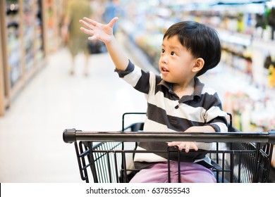 A Boy Is Shopping With His Mom In A Supermarket.