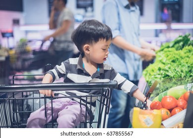 A Boy Is Shopping With His Mom In A Supermarket.