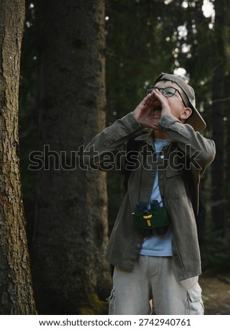 Boy shouting loudly in a forest while wearing binoculars and backpack, potentially lost or calling for help