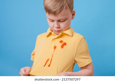 Boy Showing A Stain Spilled From Tomato Sauce And Spaghetti Dinner On His T-shirt. The Concept Of Cleaning Stains On Clothes. High Quality Photo