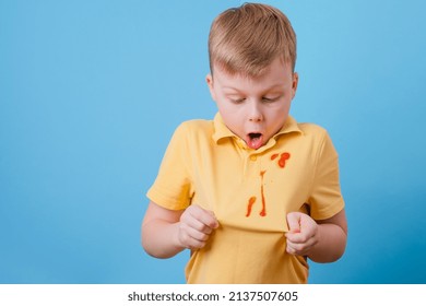 Boy Showing A Stain Spilled From Tomato Sauce And Spaghetti Dinner On His T-shirt. The Concept Of Cleaning Stains On Clothes. High Quality Photo