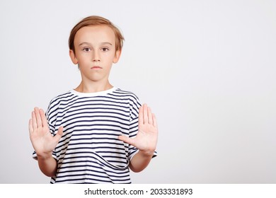 Boy Showing Stop Gesture With Palm. Children Studio Portrait. Serious School Boy Reaching Out His Hands. Child Making Stop Gesture. Signs And Symbols. Kid Doing Stop Sign With Palm Of The Hand.