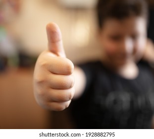 The boy shows a thumb up on his hand. Close-up