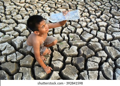 Boy Sit On Dry Ground Drinking Water.Concept Drought