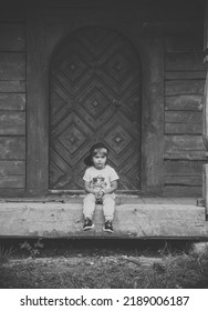 Boy Siting Next To A Wooden Door Black And White Photography