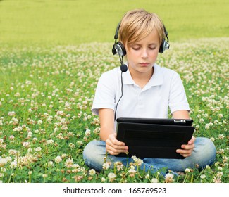 Boy sits in a park with a digital tablet