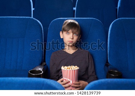 Similar – surprised boy with popcorn and television remote control on blue background