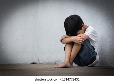 A Boy Sitting Alone With Sad Feeling. Asian Little Child Covered His Face With His Hands In Fear.  Domestic Family Violence Concept.