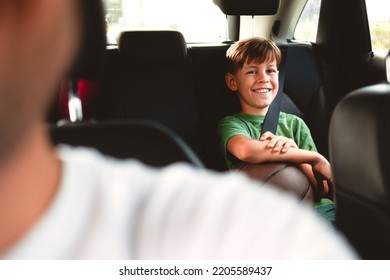 The boy is sitting in the back seat of the car, wearing a seat belt, and holding a basketball - Powered by Shutterstock