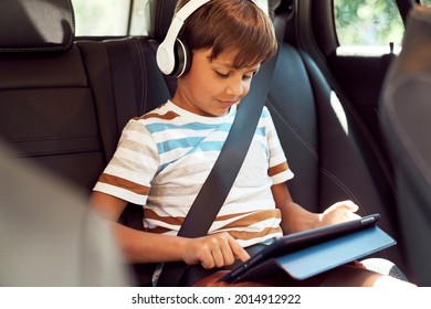 Junge sitzt mit einer digitalen Tablette im Auto                               