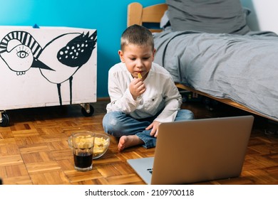 Boy Sitting In His Room Eating Junk Food And Using Laptop Computer