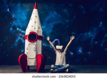 Boy Is Sitting Near Toy Rocket On Space Background And Wearing Glasses Of Virtual Reality.