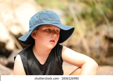 Boy Sitting On Beach Wearing Large Sun Hat