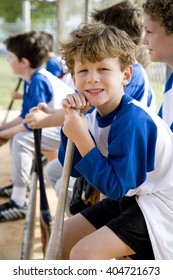 Boy Sitting On Bench With Little League Baseball Team