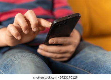  boy is sitting on the couch and using a smartphone
