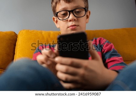  boy is sitting on the couch and using a smartphone