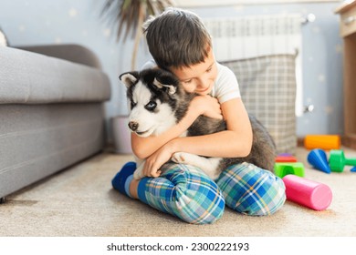 A boy sitting on the floor with his husky puppy - Powered by Shutterstock