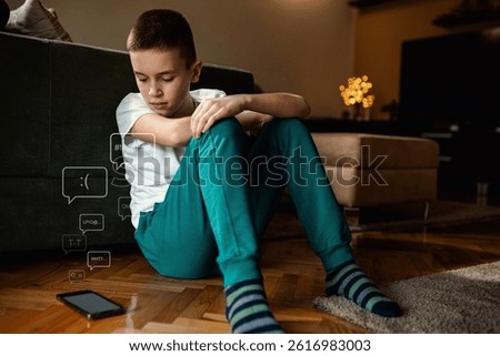 Boy sitting on floor at looking at smart phone feeling frustrated after reading bad message.