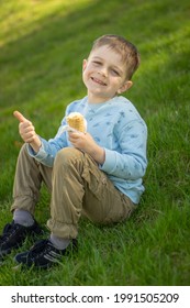 The Boy Is Sitting On The Grass. He Smiles. He Holds An Ice Cream Cone In His Left Hand And Shows A Thumb Up In His Right Hand. The Blue Sweater Has A Dinosaur Print And A GRR! Wordmark. 