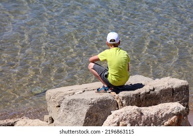 Boy Sitting On A Rock By The Sea