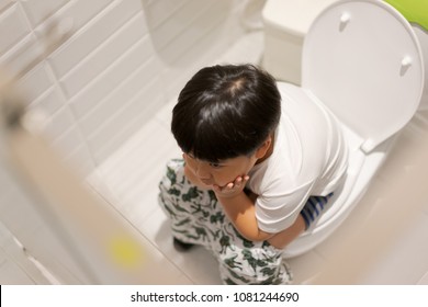 A Boy Is Sitting On Toilet With Suffering From Constipation Or Hemorrhoid.