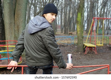 Boy Sitting In Playground Drinking Beer 