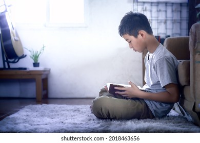 Boy Sitting And Reading Bible In Home, Discipleship Studying The Word Of God In Home.