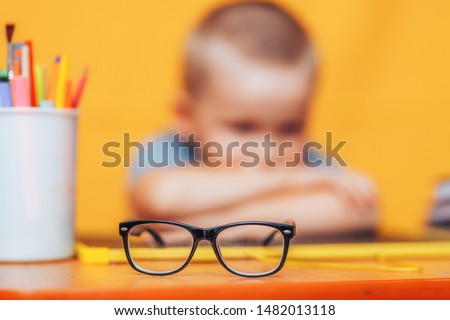boy sitting ubfocused glasses in focus. Concept problem of ophthalmology correction of myopia. back to school. Selective focus. upset child.