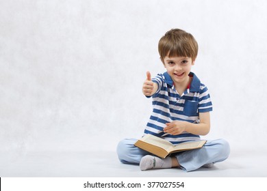 A Boy Of Six Years Old Is Reading A Book On A White Background